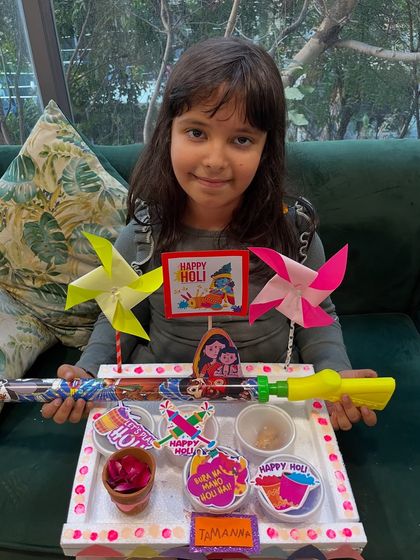 This student is all set for Holi with her creative platter, featuring pinwheels and other fun crafts.