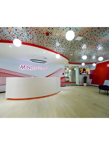The reception for Mindsprint in Bangalore makes a bold first impression. We used a curved desk, intricate perforated ceiling with globe lighting, and the company's brand colors to create a welcoming yet futuristic entrance that immediately communicates a forward thinking identity.