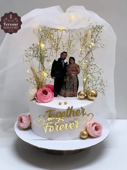 A beautiful anniversary cake that recreates a wedding memory with an edible photo of the couple. The design is enhanced with fairy lights and fresh baby's breath for a magical, dreamy effect.