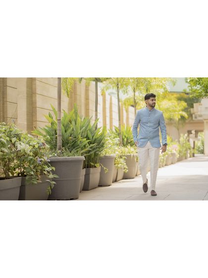 A wide shot of the groom walking in a beautifully landscaped area. This candid-style portrait captures his relaxed and confident demeanor.
