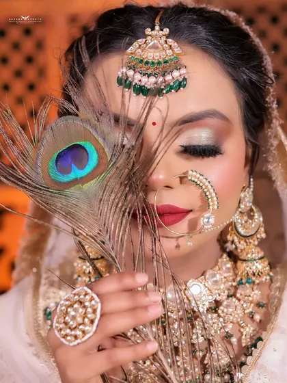 A creative close-up using a peacock feather to frame the bride's face, highlighting her eye makeup.