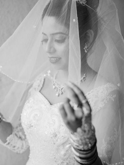 A delicate black and white portrait of the bride looking at her veil. This shot focuses on the fine details of her dress and the quiet moments before the ceremony.