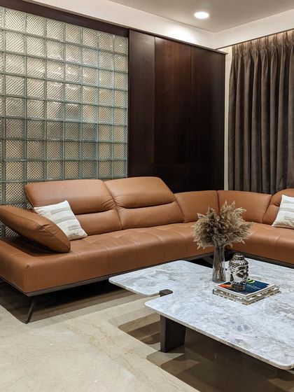 Another angle of the family lounge, highlighting the relationship between the rich brown leather of the L-shaped sofa and the dark wood paneling, creating a warm and inviting atmosphere.
