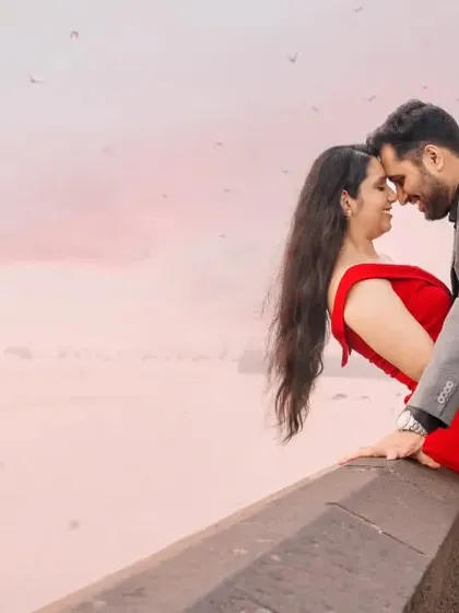 A candid and romantic moment overlooking the water in Mumbai. The soft pink sky and the gentle interaction between the couple create a dreamy and heartfelt urban portrait.