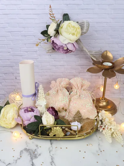 A beautiful wedding trousseau hamper, featuring elegant stationery, sequined potlis, and a decorative candle holder on a golden tray.