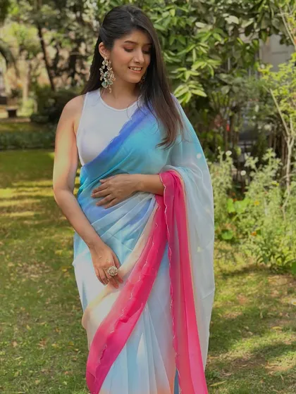 This colorful ombre saree is a beautiful and bold choice for a celebration like Holi. Paired with a simple white sleeveless blouse, the focus remains on the vibrant colors of the saree itself.