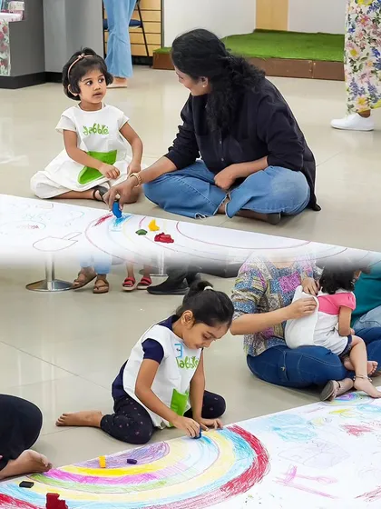 A parent and child collaborate on a large floor drawing, creating a colorful rainbow. These shared art experiences are perfect for family bonding.