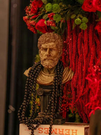 It's all in the details. A classical bust, juxtaposed with modern luxury elements and vibrant red florals, adds an artistic and eclectic touch to the decor.