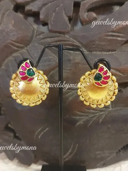 These Dakshinaya studs feature a beautiful combination of pink and green stones on a textured gold base, offering a classic and colorful look suitable for any festive occasion.