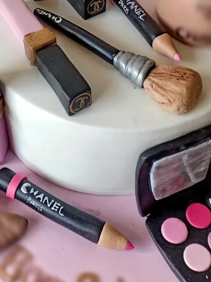 Another angle of the makeup cake, showing the handcrafted lipstick, eyeliner pencil, and brushes.