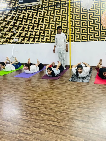 I make sure to walk around and observe everyone's form during class. Here, I am guiding the group through Dhanurasana, the bow pose, to ensure everyone is safe and getting the most from the posture.