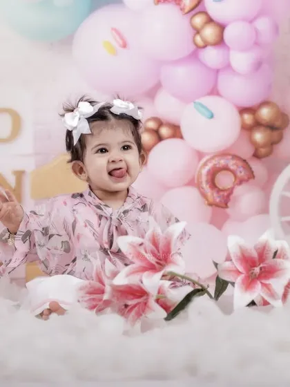 A playful moment captured amidst a cloud of soft fluff and pastel balloons. Her cheeky expression shows the fun and relaxed nature of our themed birthday shoots.