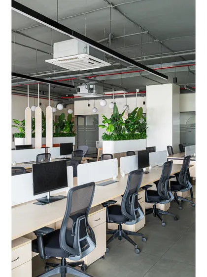 Another view of the open-plan workstation area, highlighting the exposed ducting and services on the ceiling, painted to blend in. The design is honest and functional, celebrating the structural elements of the building.