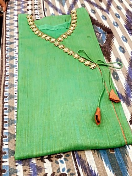 Another view of the green kurta with an angrakha-style neckline, detailed with a floral lace border and matching tassels.