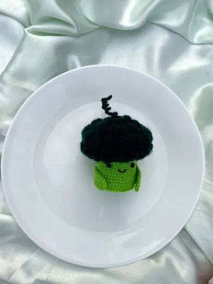 A close-up of the happy little crochet broccoli character.