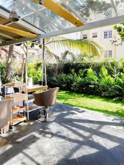 The styling stations at Enrich Salon are placed in a glass-enclosed pavilion, offering serene views of the surrounding greenery. The design ensures that even air-conditioned indoor spaces are flooded with diffused natural light filtered through the onsite trees.