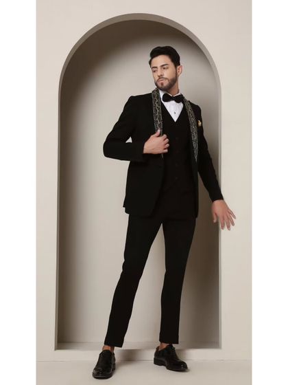 The Gilded Onyx Majesty tuxedo, shown here as a three-piece ensemble. The embellished lapel remains the focal point, complemented by a matching waistcoat for a layered, formal look.