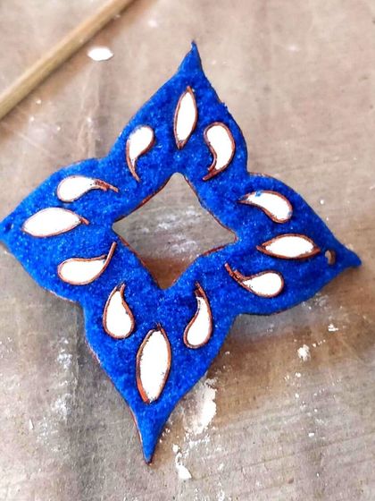 An intricate blue and white enamel piece, ready to be turned into a pendant or part of a larger jewellery design.