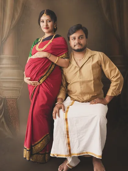 A classic portrait of an expecting couple in traditional veshti and saree, capturing the timeless elegance of South Indian culture.