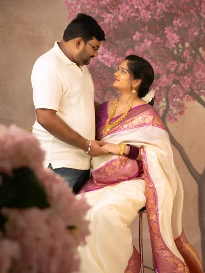 A beautiful shot of the couple holding hands and sharing a look of love. The foreground flowers add depth to the image, framing this tender moment perfectly.