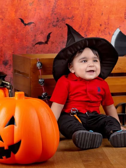 This little witch is all smiles, sitting next to a big pumpkin in our Halloween scene.