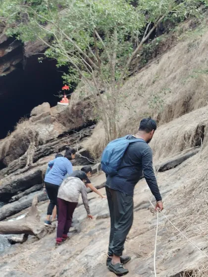 Using a rope for support while climbing a slippery rock face to get to a cave entrance. Safety is always my priority.