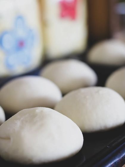 Dough balls proofing on a tray, the crucial step before baking. We teach the entire bread-making process from start to finish.