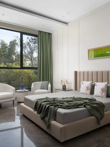 This bedroom is a peaceful retreat, with a large window framing the lush green landscape outside. The color scheme of beige and sage green echoes the natural tones, creating a harmonious and restful space.