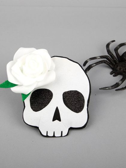 The skull hair clip styled with a toy spider for a spooky effect.