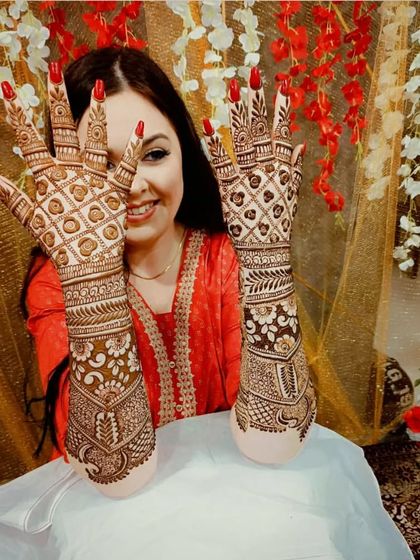 This happy bride is showcasing her full-coverage back-hand mehandi. The design is a classic jaali pattern with detailed borders.