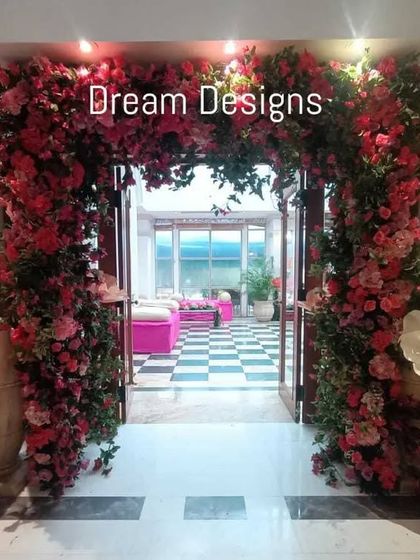A grand floral entrance I designed for a special event. The arch is overflowing with pink bougainvillea and accented with large, whimsical paper flowers, creating a joyful and dramatic welcome.