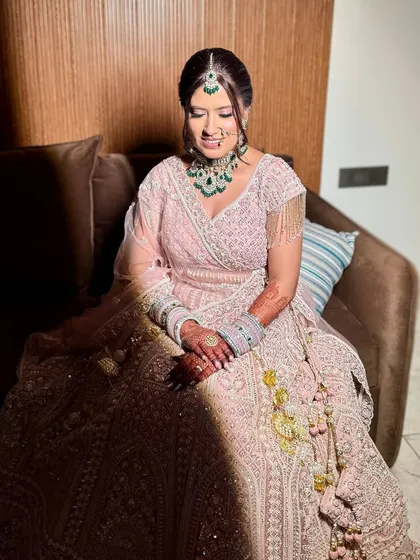 A beautiful, serene moment of the bride. The soft lighting highlights her glowing makeup and the intricate details of her lehenga.