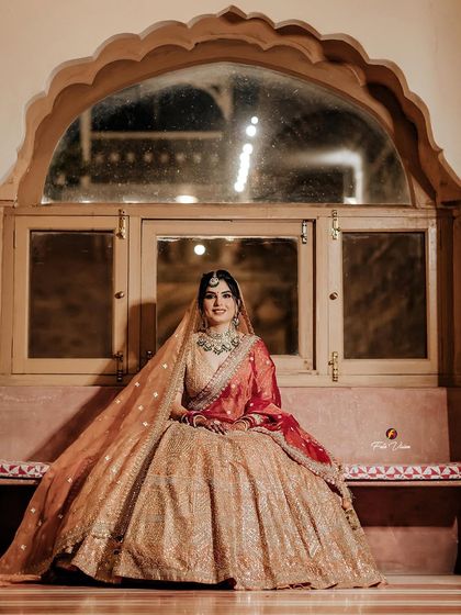 A lovely portrait of the bride seated by a traditional arched window, looking serene and beautiful.