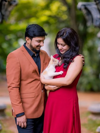 An intimate moment with a kitten, framed by ornate stone pillars and the natural green backdrop of the garden.