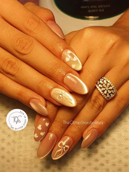 A soft and romantic bridal set. Almond-shaped nails with a cat-eye base are decorated with hand-painted white hearts and bows for a sweet and delicate look.