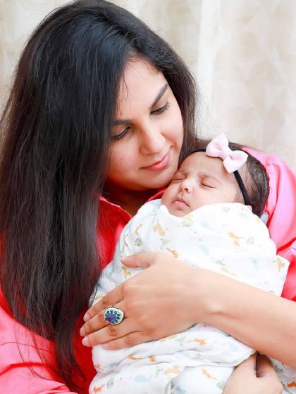 A mother's loving gaze as she holds her sleeping newborn. Our lifestyle sessions are about capturing the natural bond and emotion in the comfort of your own home.