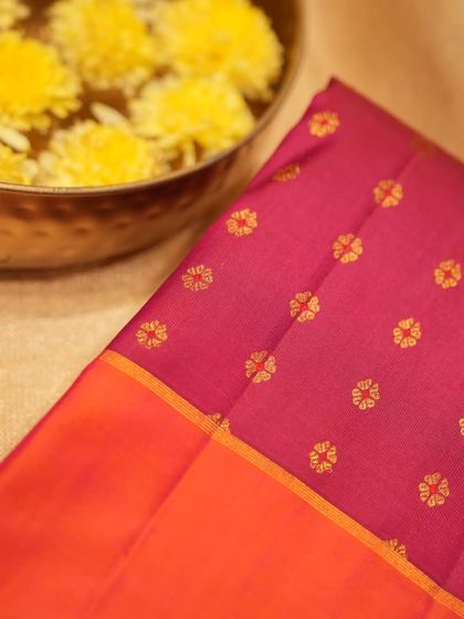 A close-up of the small floral buttas woven in gold zari on the maroon Kanjivaram.