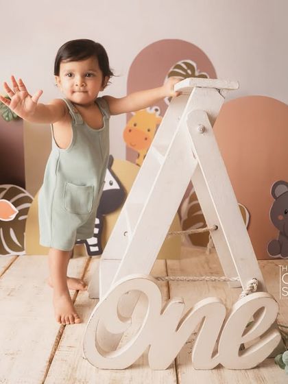 Waving hello from the jungle. This one-year-old is the king of his wild-themed birthday celebration.