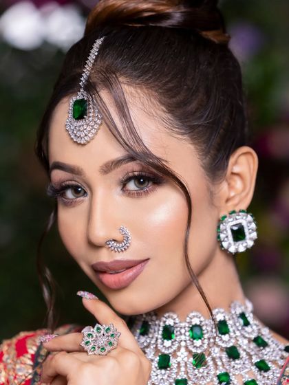 A new-age bridal look with soft smokey eyes, nude lips, and beautiful emerald and diamond jewelry.