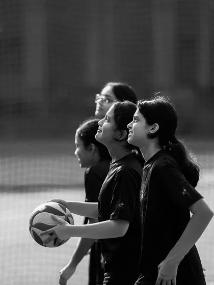 Young players look up, tracking the ball with hopeful anticipation. This black and white photo highlights their shared focus and dreams.
