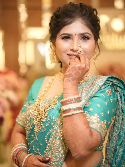 The traditional nath is the centerpiece of this look, perfectly complementing her soft and glamorous makeup.