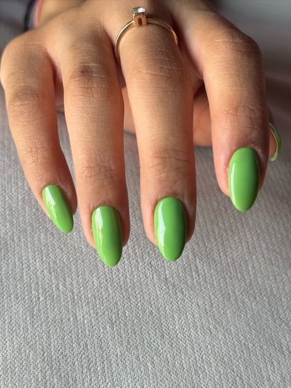 A close-up of the glossy, bright green manicure.
