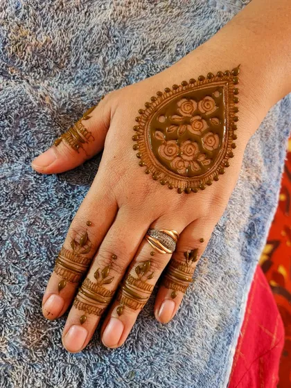 This design features a single, bold paisley filled with delicate roses on the back of the hand, with simple bands on the fingers.