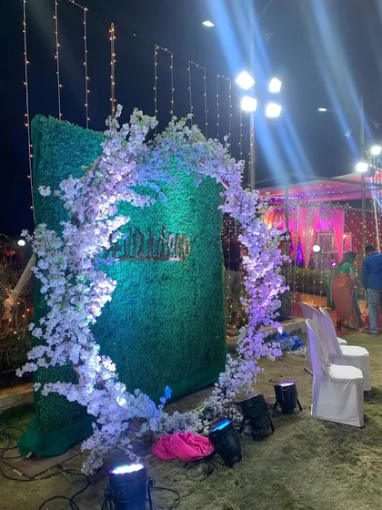 Another view of a circular photo arch, this time placed on a greenery wall. The white blossoms are lit with purple uplighting, creating a dramatic effect for evening events.