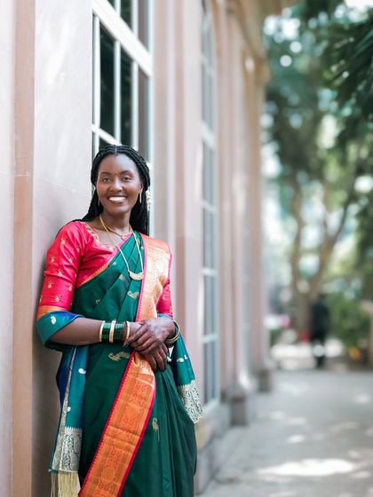 A beautiful portrait of a bride in a traditional green and red silk saree, her smile lighting up the frame.