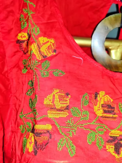A close-up of the delicate cross-stitch hand embroidery on the orange cotton top. Every piece is made with care and attention to detail, reflecting the heart of my small business.