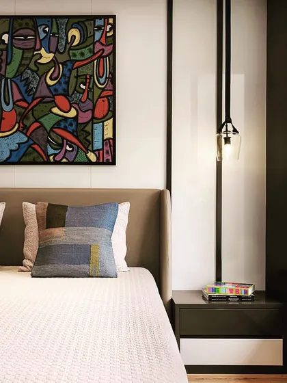 The second apartment features a more modern and art-focused design, with a bold painting serving as the centerpiece of the bedroom.
