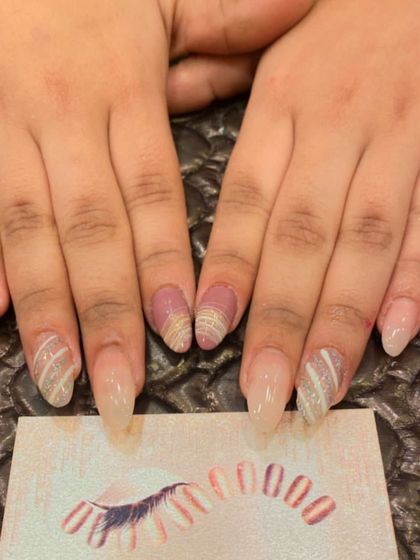 A unique design on long, clear stiletto nails. The accent nails feature a textured, striped pattern using glitter and a solid mauve color.