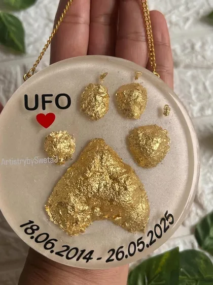 The second memorial plaque, this one featuring the pawprint covered in shining gold leaf. The gold represents how precious UFO's memory is, set against a soft, pearly white background.