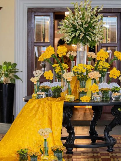 My Haldi Hues table setting blossoms with the vibrancy of yellow sunflowers and roses. A cascading yellow drape completes the look, creating a tapestry of warmth and love for this enchanting celebration.